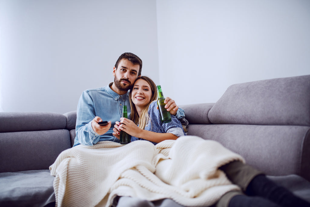 Man and woman cuddling on couch with blanket 